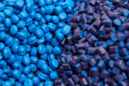 Zbliżenie na dwa stosy niebieskich plastikowych granulek polipropylenu na stole
